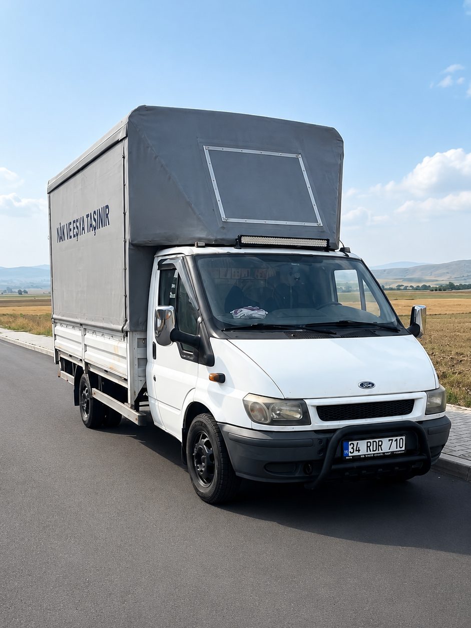 Karamanlı Nakliyat'a ait Ford Transit kamyonet yol kenarında; kasa brandayla kapalı, yanında firma yazısı.